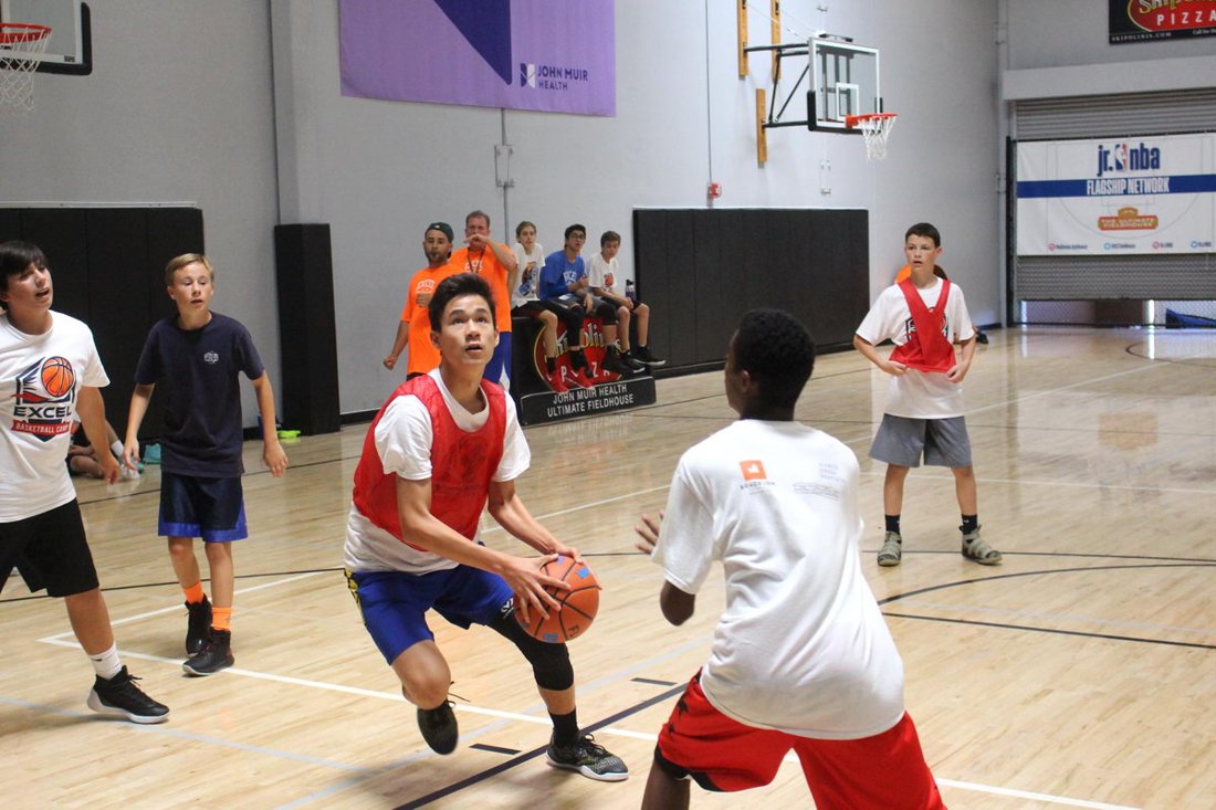 Excel Basketball Camp participants playing basketball at the Ultimate Fieldhouse in an official program photograph
