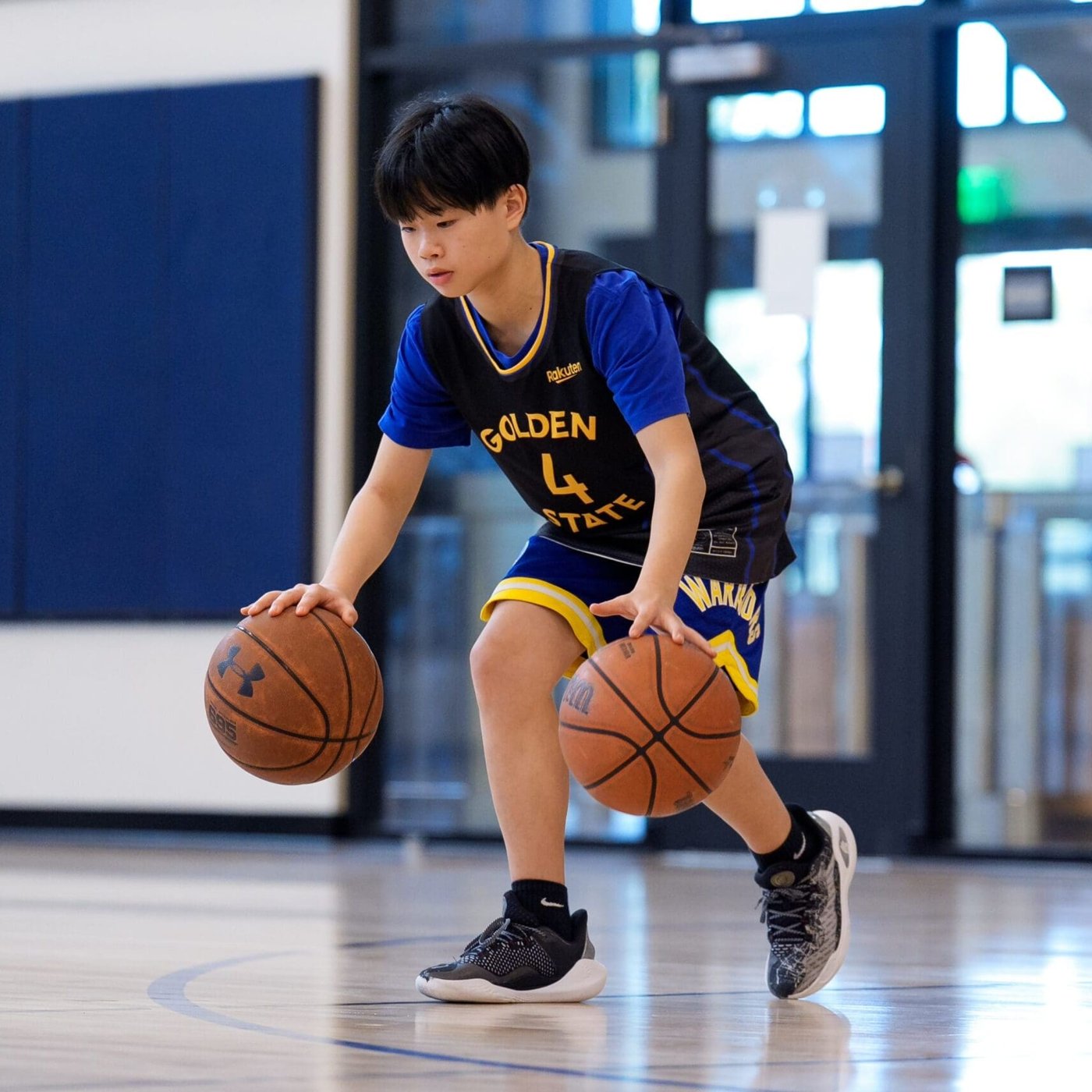 A participant practicing with two basketballs in an official Golden State Sports Academy camp photograph